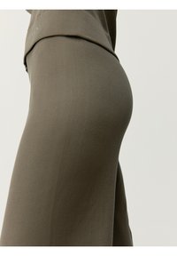 Žebrované olivovo zelené šaty s priliehavým strihom, vyrobené z elastického materiálu. Obsahujú drapovaný výstrih a bezšvový dizajn.