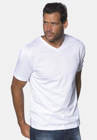 Hvid bomulds V-hals t-shirt med korte ærmer, der har en glat tekstur og en afslappet pasform. Bæres med blå denim jeans.