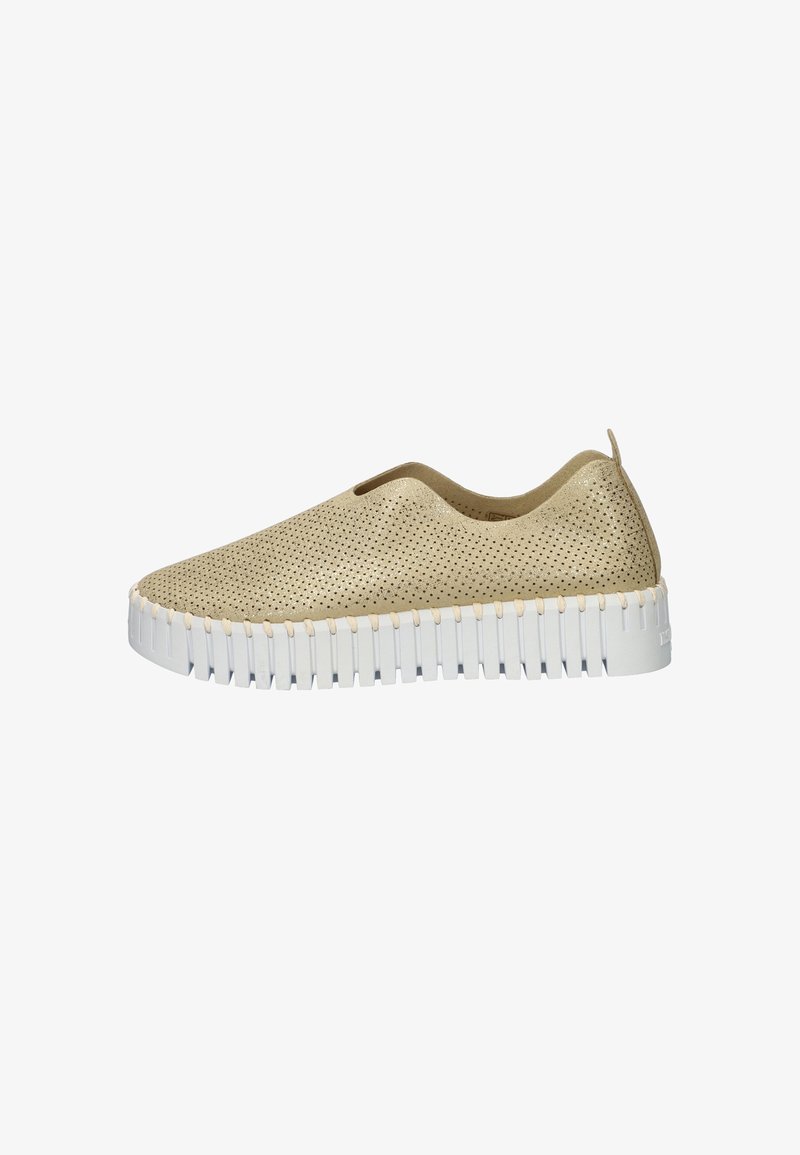 Zapato slip-on perforado beige con suela blanca acolchada y estriada. Presenta un diseño minimalista y un lado elástico para facilitar el uso.