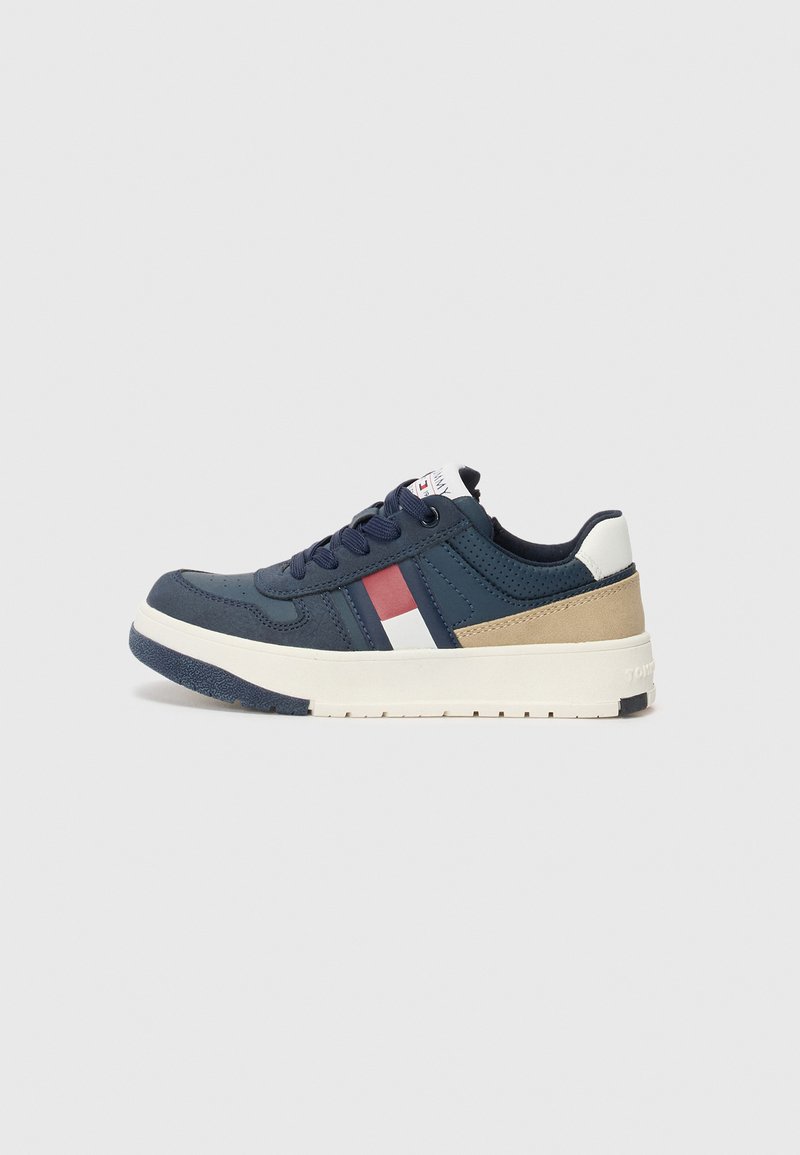 Baskets bleu marine avec une tige texturée, des accents blancs et rouges, et une semelle intermédiaire crème avec un talon renforcé pour la stabilité.