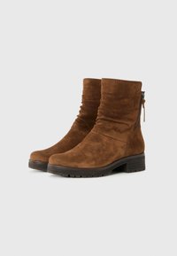Braune Wildleder-Ankelstiefel mit geschopptem Design, ausgestattet mit einem seitlichen Reißverschluss und einer strukturierten Gummisohle für besseren Halt. Der Blockabsatz sorgt für Stabilität.