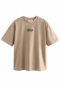 Camiseta oversized beige de algodón con cuello redondo. Presenta el texto negro "AMSTERDAM" impreso en la parte frontal. Mangas cortas.