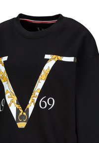 Zwarte sweatshirt met een opvallend wit en goud 'V'-ontwerp met verfijnde details, vergezeld van '69' eronder. Ronde hals, zachte stof.