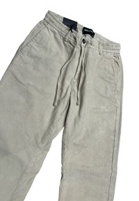 Pantaloni in velluto a coste beige con un design a righe testurizzate, vita elastica, chiusura con coulisse e due tasche laterali.