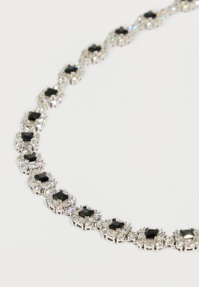 Κολιέ σε ασημί τόνο με εναλλασσόμενες μαύρ�ες και διάφανες πέτρες σε στήριξη με νύχια, με κομψό σχεδιασμό και ομαλή υφή.