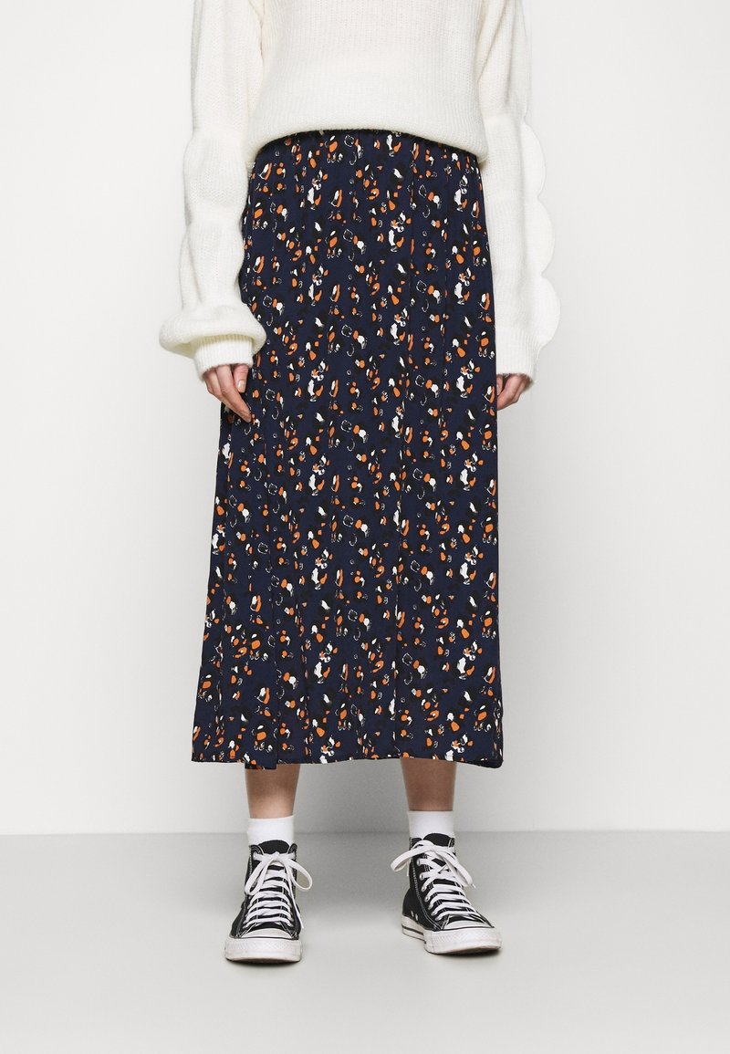 Mörkblå blommig midi kjol med en avslappnad midja, med orange och vita mönster. Matchad med svarta hög-top sneakers.