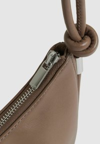Geantă de mână din piele maro, cu un fermoar argintiu, accente texturate și o mână legată pentru un detaliu de design unic. Formă compactă și bine structurată.