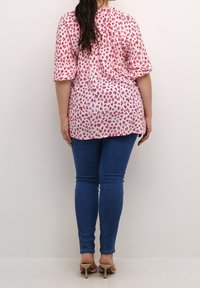 Lyserød og hvid leopardprint bluse med korte pufærmer, parret med blå skinny jeans og beige hælede sandaler.