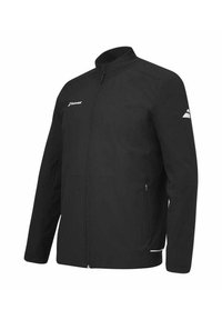 Chaqueta softshell negra con cuello alzado, cremallera completa, bolsillos laterales y detalle del logo blanco en el pecho y el brazo. Textura suave.