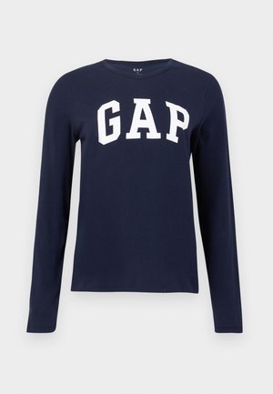 Tumesinine pikavarrukatega särk, millel on valgel taustal rinna keskel valge "GAP" tekst.