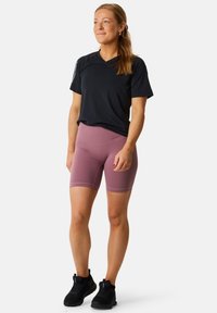 Sort trænings T-shirt og lyserøde cyk shorts, der har et tætsiddende design og glat tekstur. Sorte træningssko.