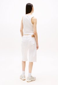Valge ribadega tank top, millele on sobitatud kõrge vöökohaga valged denim lühikesed püksid. Jalatsiteks on heledat halli värvi tossud, mille kaudu on nähtavad valged sokid.
