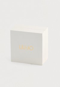 Biely obdĺžnikový box so zlatým logom "LIU·JO" umiestneným na prednej strane, položený na svetlom neutrálnom pozadí.