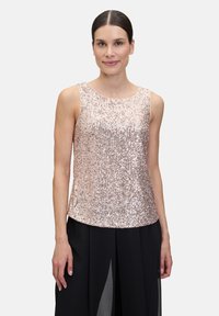 Różowy cekinowy top na ramiączkach z okrągłym dekoltem, bez rękawów, dopasowany w talii, zestawiony z luźną czarną spódnicą z rozcięciami.