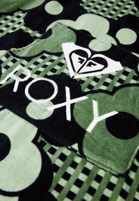 Vihreä ja musta fleece-peite, jossa on pyöristettyjä kuvioita, ruudullinen suunnittelu ja valkoinen logo, jossa lukee "ROXY".