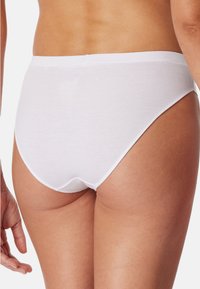 Culotte en coton blanc avec une texture côtelée, présentant une large taille élastique et une couverture arrière complète, vue de côté.