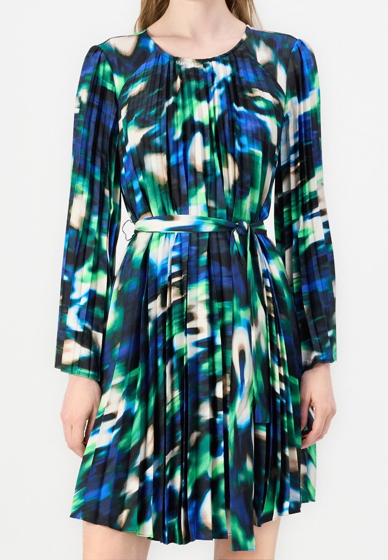 Robe plissée à manches longues avec un motif abstrait bleu, vert, noir et blanc et une ceinture à nouer assortie à la taille.