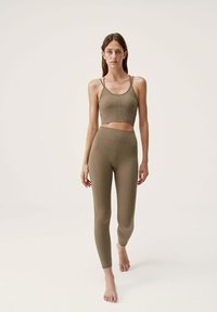Bruine geribbelde sportbh en strakke leggings, met dunne banden en een hooggekorte pasvorm met subtiele naaddetails.