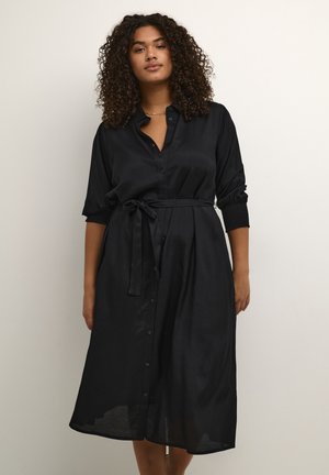 Black button-up dress made of smooth fabric, featuring a belted waist, three-quarter sleeves with gathered cuffs, and a mid-length hem.