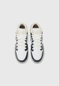 Zapatillas de cuero negras y blancas con puntera perforada, cordones planos blancos, cuello acolchado y branding dorado en la lengua.