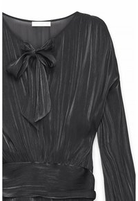 Melnas garām piedurknēm blūze ar gurnu tekstūru, priekšējo loku kakla apgabalā un platām jostām.