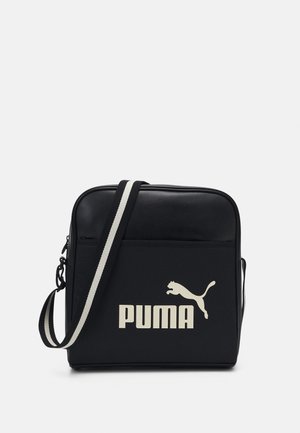 Sac bandoulière Puma noir et blanc avec sangle réglable et logo audacieux sur la poche avant, forme rectangulaire, section supérieure lisse.