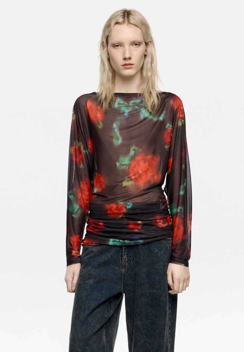 Przezroczysta czarna bluzka z długim rękawem w czerwony kwiatowy wzór z zielonymi akcentami, z marszczoną fakturą w talii i okrągłym dekoltem.
