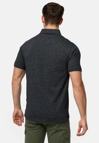 Polo shirt court gris foncé à manches courtes avec une finition texturée, doté d'un col classique et d'une coupe ajustée, associé à un pantalon vert olive.