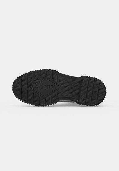 Semelle de chaussure noire avec motif de bande de roulement texturé et le mot "ADIEV" embossé en forme de losange au centre.