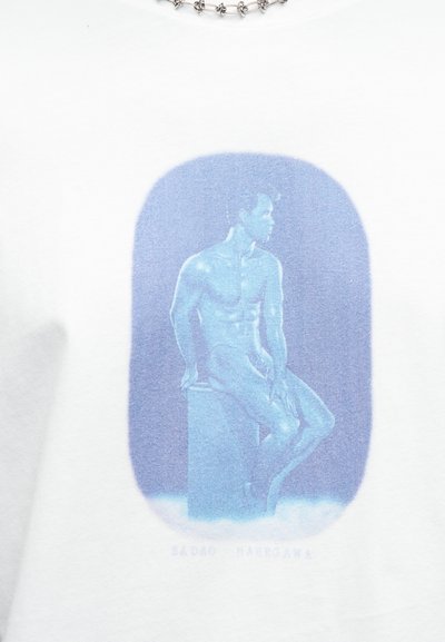Λευκό βαμβακερό μπλουζάκι με μπλε γραφικό σχέδιο που απεικονίζει έναν καθιστό ανδρικό φιγούρα, περιγραφόμενο σε ένα απαλό οβάλ σχήμα, εμφανιζόμενο πάνω από ένα βάθρο.