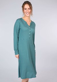 Langärmliges Kleid in Petrol mit geometrischem Muster, ausgestattet mit einem geknöpften V-Ausschnitt, weichem Stoff und seitlichen Schlitzen für Bewegungsfreiheit.