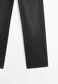 Jean en denim noir à coupe droite, montré du genou vers le bas sur fond blanc.