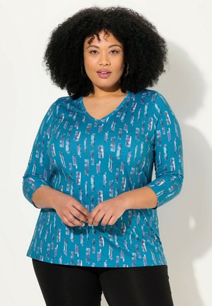 Teal lange mouwen top met een V-hals, voorzien van een patroon van verticale penseelstreken in tinten blauw en paars, gemaakt van een zachte stof.