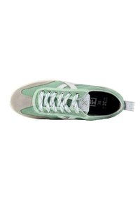Zapatillas de lona verdes con acentos de ante beige, cordones blancos y un logo en la lengüeta. Presenta una puntera redondeada y suela de goma plana.