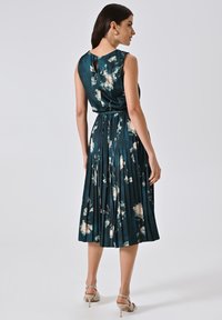 Faltenkleid aus dunkeltürkisem Satin mit floralem Muster, ärmelloses Design und Schlitzdetail auf der Rückseite. Leichter und fließender Stoff.