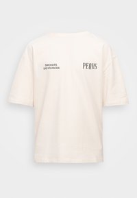 Jasno-beżowa, oversize koszulka wykonana z miękkiej bawełny. Na plecach czarny nadruk: "PALACZE UMIERAJĄ MŁODZIEJ" oraz "PEQUS".