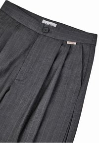 Pelēki svītraini bikses, izgatavotas no mīksta auduma ar plecu priekšpusi, piedāvā vienas pogas aizdari un zīmolu etiķeti tuvu jostasvietai.