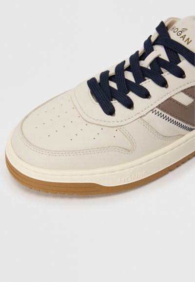 Beige bőr sneaker navy fűzőkkel, perforált orral, barna kiegészítőkkel, gumitalppal és emboszol logo-val az oldalon.