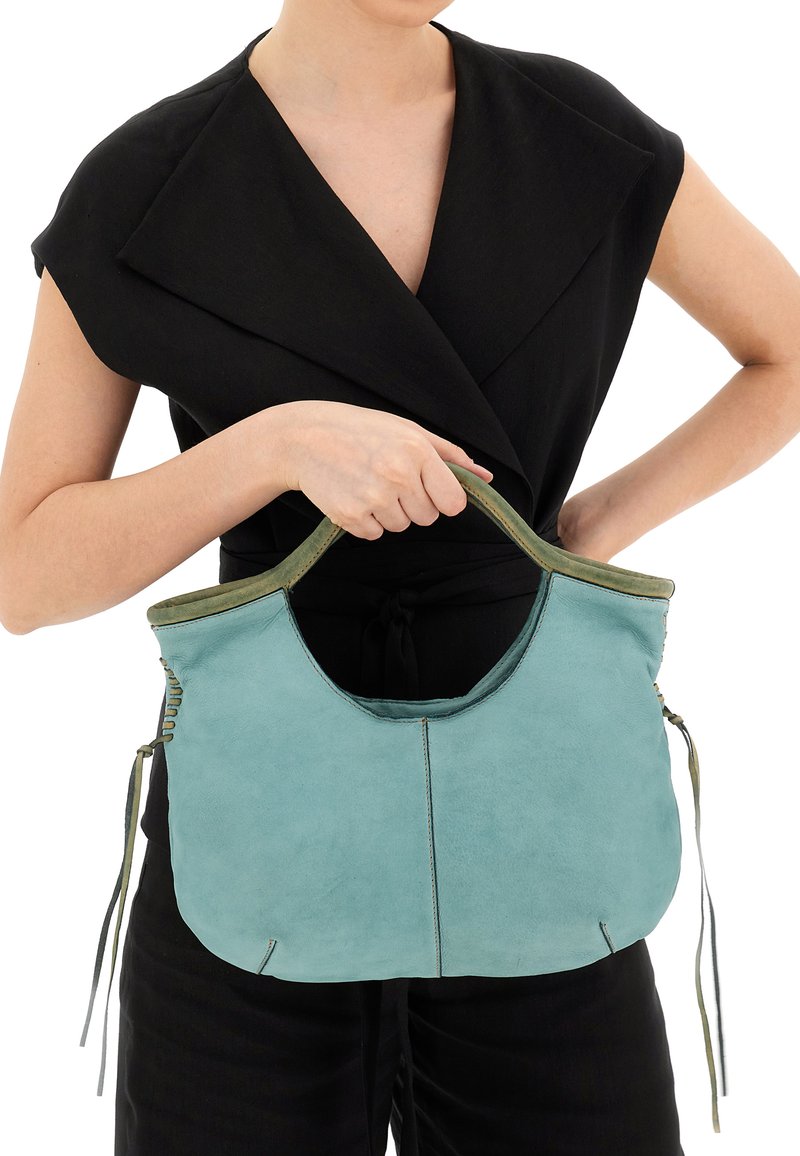 Una borsa a tracolla in pelle color turchese con una texture liscia, forma arrotondata, manico superiore e legature decorative sui lati. L'interno è di un verde contrastante.