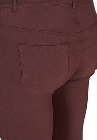 Maroon traperice sadrže stražnji džep s urednim, šivanim obrubom. Tkanina ima glatku, blago teksturiranu završnu obradu.