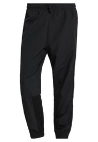 Svarta träningsbyxor med tapered passform, elastisk midja och kontrasterande paneldetaljer på sidorna; smidigt, lätt tyg.