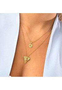 Collier en or avec un pendentif en forme d'éléphant et un charme circulaire gravé avec "M". Design de chaîne délicate avec un léger éclat.