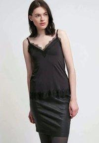 Svart satin kamisol med blondedetaljer rundt utrigningen og kanten, parret med et svart skinnminijors, som har en slank passform og glatt tekstur.