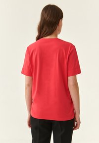 Rotes T-Shirt mit kurzen Ärmeln und rundem Halsausschnitt, aus weichem Stoff gefertigt, mit gerader Silhouette und sauberem Saum.