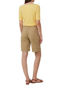 Chemise courte à rayures jaunes et blanches, shorts beiges roulés et sandales marron. Dotée d'une coupe décontractée et de deux poches arrière sur les shorts.