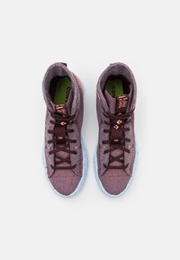 Vyšší tenisky vyrobené z texturované burgundské látky s oranžovými akcenty, hnědými tkaničkami a světle modrou gumovou podešví.