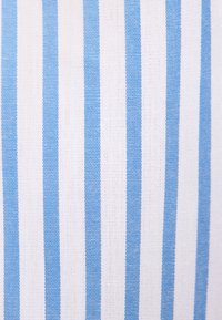 Des rayures verticales bleues uniformément espacées sur un fond en tissu blanc tissé.