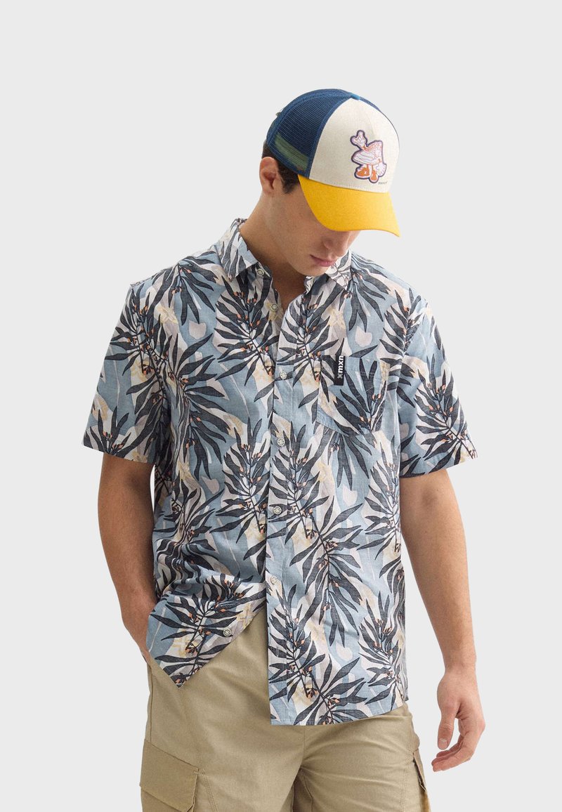 Košeľa s krátkym rukávom modrej farby s listovým vzorom, s gombíkmi a vreckom na prsiach. Doplnkovaná modro-žltou čiapkou.