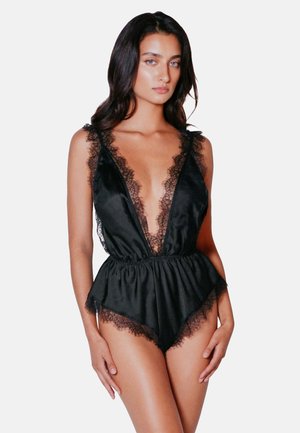Black bodysuit featuring lace trim along the deep V-neckline and legs, with a flowing silhouette and delicate texture.