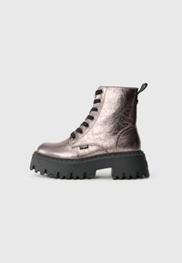 Bota de combate de cuero metálico rosa con suela gruesa negra, cordones negros y etiqueta de marca en el costado, sobre un fondo gris claro.